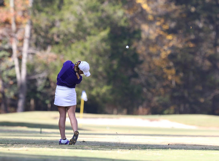 A Converse student swings a golf club