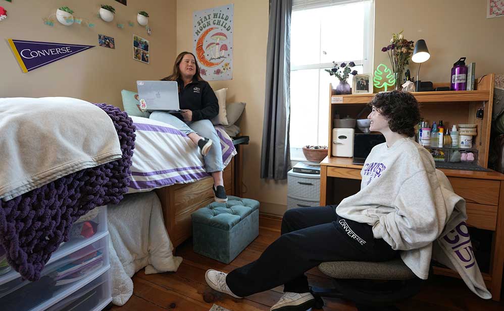 Residential students sit together in a dorm room.