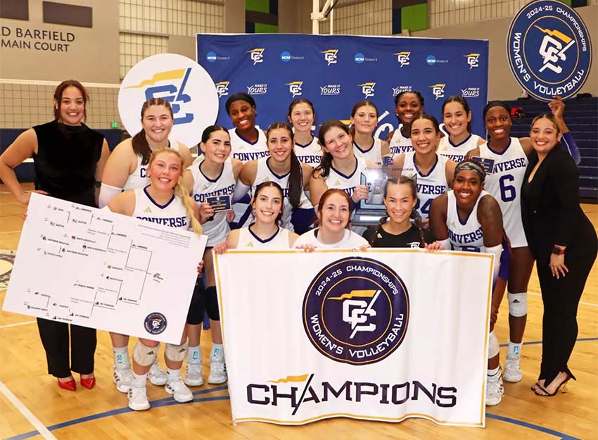 The Converse volleyball team stands with their coaches holding up a championship banner.