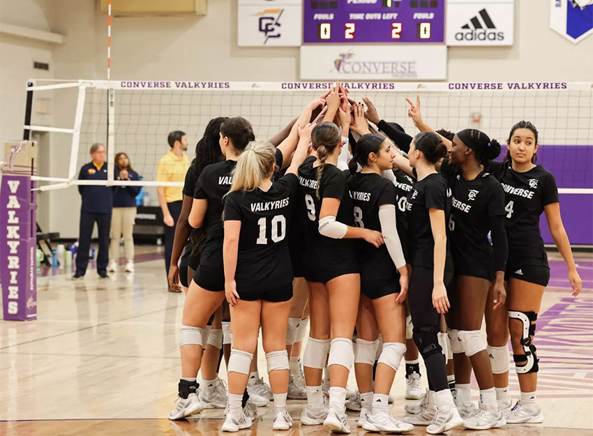 The Converse volleyball team high fives each other after a win.