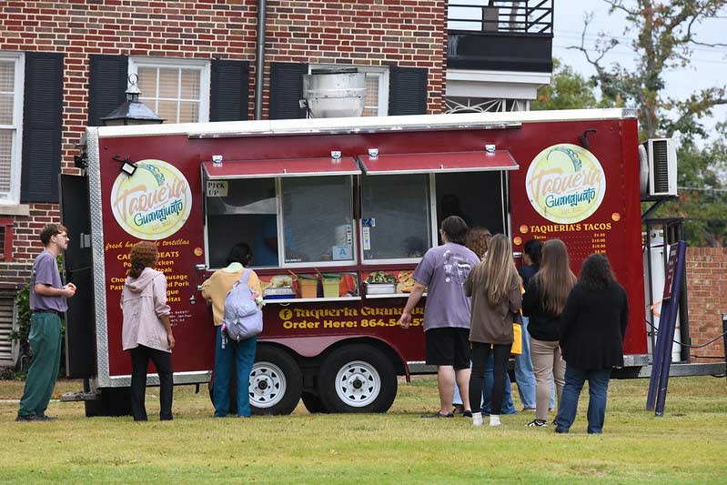 Guests at homecoming line up at one of the food trucks on the campus quad.