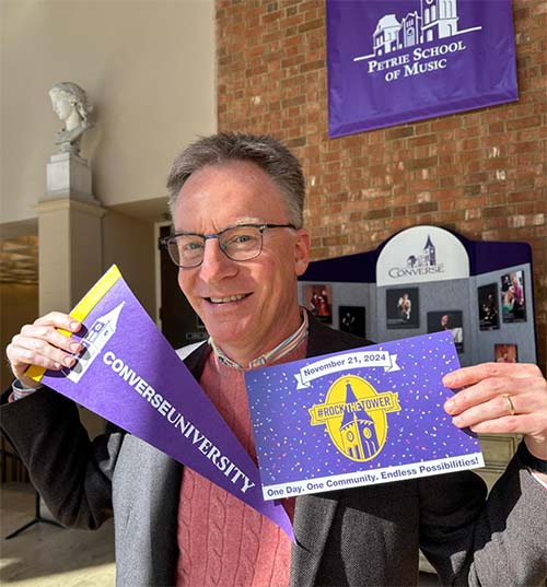 Dean of the School of the Arts Dr. Chris Vaneman holds up signs of support for Rock the Tower in Blackman Hall