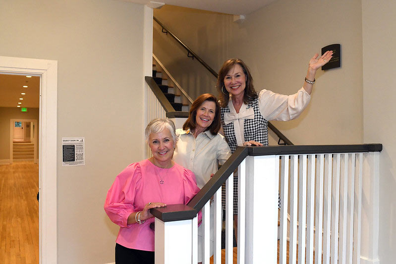 Converse alumnae stand on the refurbished stairs inside Cudd hall smiling.