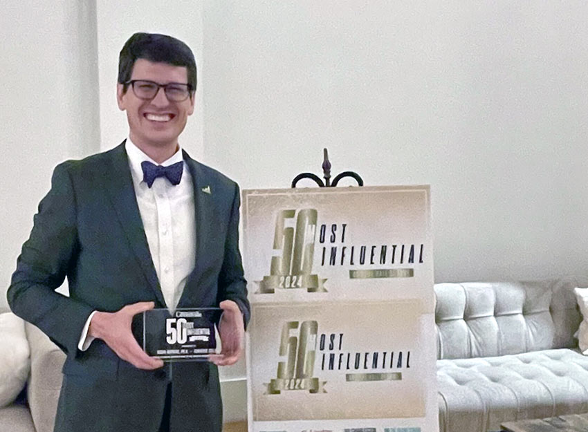 Dr. Hopkins stands smiling holding his award commemorating him as one of the most influential people in the SC region.