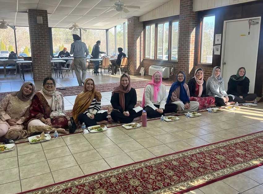 Converse students of various faiths sit on the floor at a place of worship
