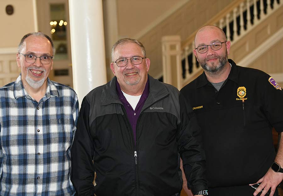 Sergeant Lannie Rudicill, Larry Jones, and Fire Marshal Kyle Crowder stand smiling in Wilson Lobby on the Converse campus.