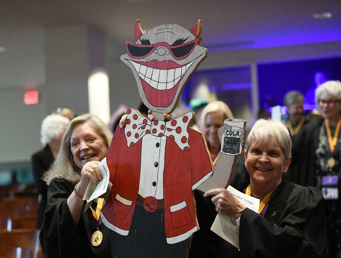 Two members of the Class of 1975 carry a cardboard cutout of their 'Red Devil" mascot.