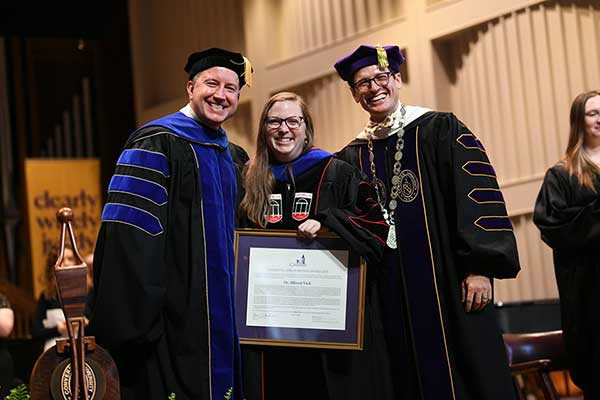 Dr. Will Case, Dr. Allison Vick, and President Boone Hopkins on stage presenting the award.