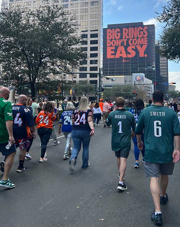 Fans walk along a city street during the Super Bowl Experience.